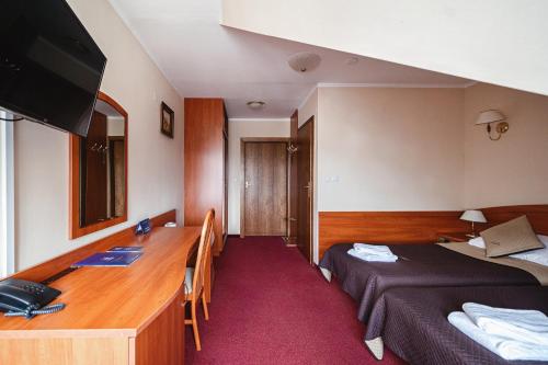a hotel room with a desk and a bed at Kompleks Antałówka Termy & Med in Zakopane