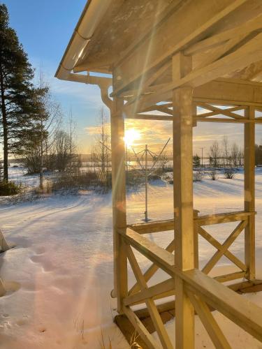 a wooden gazebo in a snowy field with the sunset at HusHotellHunge AB in Bräcke