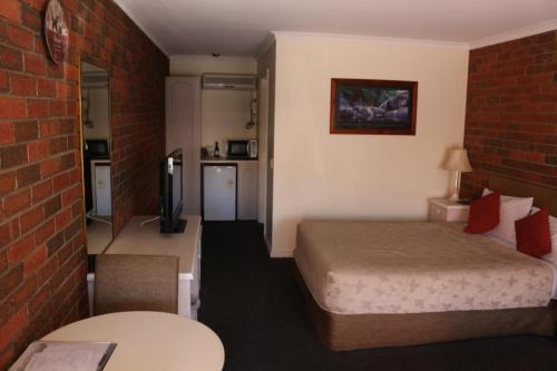 a hotel room with a bed and a brick wall at Bendigo Haymarket Motor Inn in Bendigo