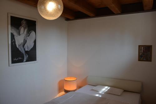 een slaapkamer met een bed met een lamp en een foto bij Apartment Magalita in Udine