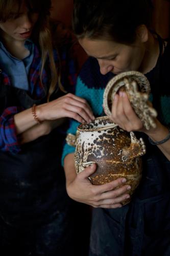 a woman is holding a pot with her hands at Amatų kalnelis in Anykščiai