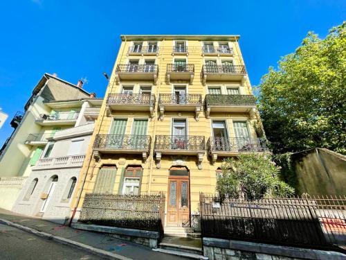 wysoki żółty budynek z balkonami przy ulicy w obiekcie Studio centre ville avec ascenseur 3min des thermes w Aix-les-Bains