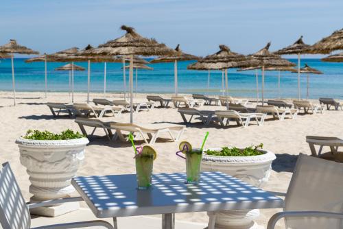 a sandy beach with tables and chairs and umbrellas at JAZ Tour Khalef in Sousse