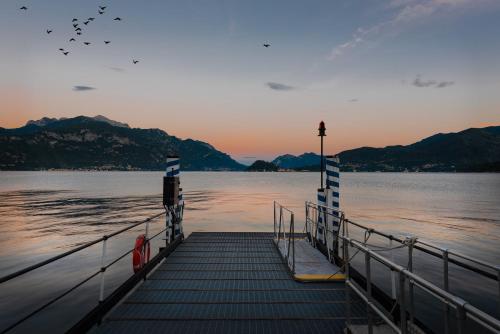 a dock on a body of water with mountains at Hotel Garni Corona in Menaggio