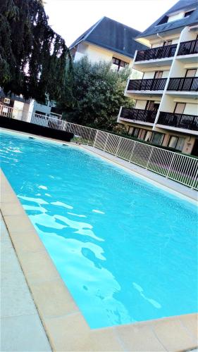 a large blue swimming pool next to a building at Appartement refait à neuf résidence avec piscine Trouville sur mer in Trouville-sur-Mer