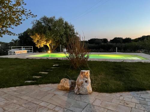 a couple of rocks sitting on the grass near a tennis court at Trullo Nadia Ostuni in Ostuni