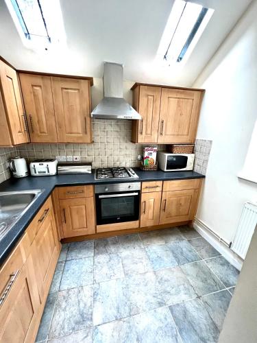 a kitchen with wooden cabinets and a stove top oven at 4 St Richard’s Cottages in Fittleworth