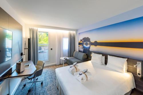 a hotel room with a large bed and a desk at Novotel Toulouse Centre Compans Caffarelli in Toulouse