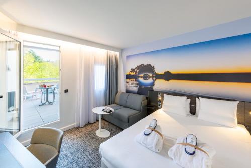 a hotel room with a large bed and a chair at Novotel Toulouse Centre Compans Caffarelli in Toulouse