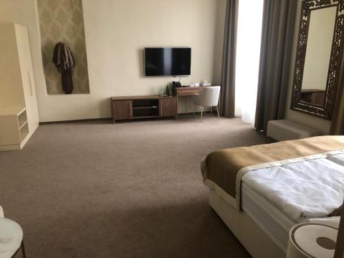 a hotel room with a bed and a television at Hotel Panství Dlouhá Lhota in Dlouhá Lhota