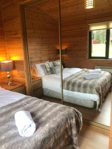 a bedroom with two beds in a wooden cabin at Lomond Lodge in Rowardennan