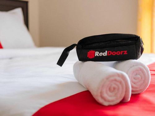 a red book bag on a bed with towels at RedDoorz at Hotel Rumberpon Sorong in Sorong