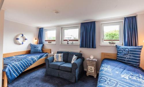 a bedroom with a bed and a chair and a couch at Terrassen-Fewo-Heimathaven-direkt-am-Ostseestrand in Kronsgaard