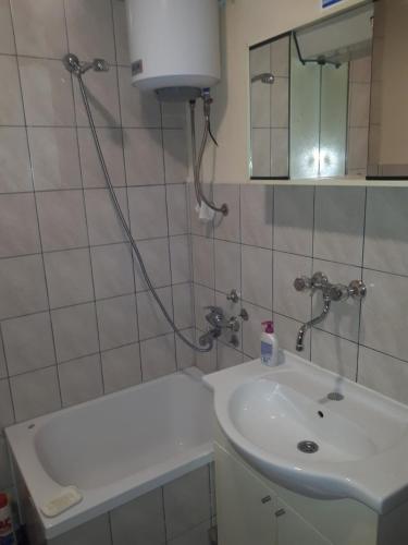 a bathroom with a sink and a tub and a mirror at Relax house in Visoko