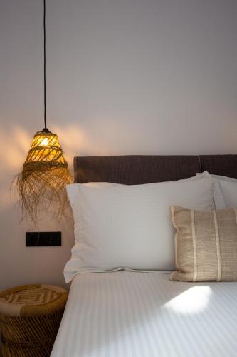 a bed with a white pillow and a lamp at Eleana Hotel in Tinos Town