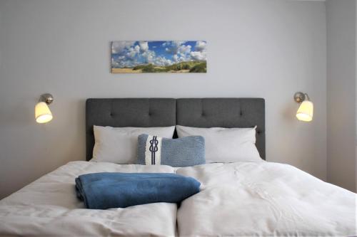 - une chambre avec un grand lit blanc et des oreillers bleus dans l'établissement Küstenscheune, à Kirchdorf