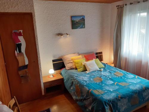 - une petite chambre avec un lit et des oreillers colorés dans l'établissement Gîte dans hameau, à Ugine