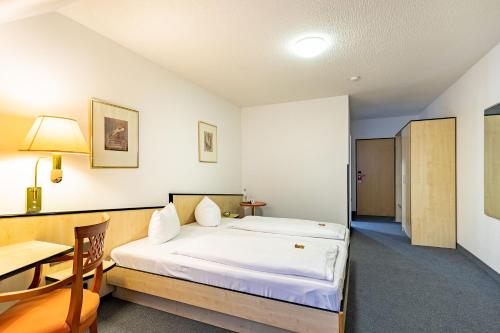a bedroom with a bed and a table and a desk at Waldhotel Eskeshof in Wuppertal