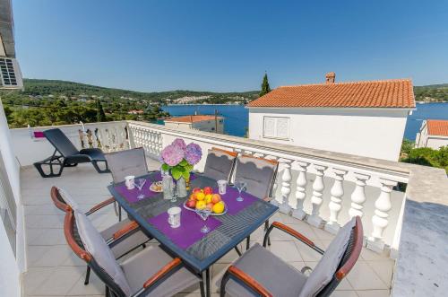 a table with fruit and flowers on a balcony at Apartment Zvonimir in Nečujam