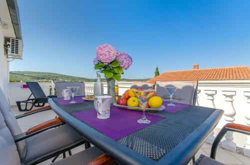 a table with a plate of fruit and flowers on a balcony at Apartment Zvonimir in Nečujam