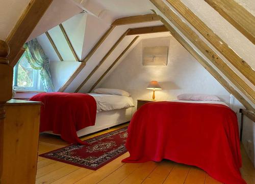 a attic bedroom with two beds with red sheets at Snow Whites House - Farm Park Stay with Hot Tub in Swansea