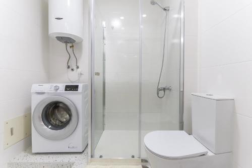 a white bathroom with a washing machine and a shower at Vita Portucale ! Cacilhas River View in Almada