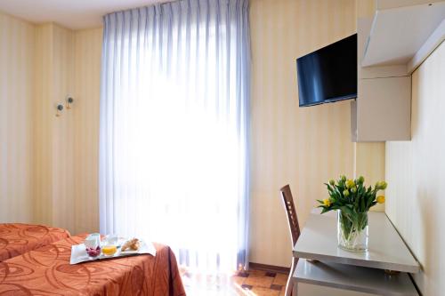 ヴィアレッジョにあるHotel Mirageのベッド、テーブル、テレビが備わるホテルルームです。
