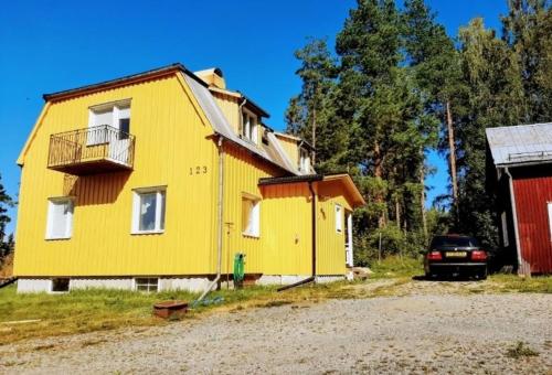 a yellow house with a car parked in front of it at Cheerful 1-bedroom, 120 m from Sandbach in Bräcke