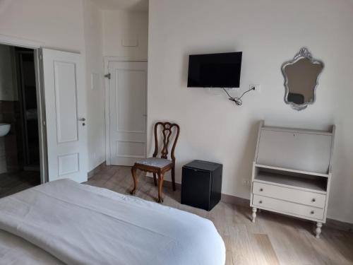 a bedroom with a bed and a chair and a television at Hotel Villa Bonelli in Fiesole