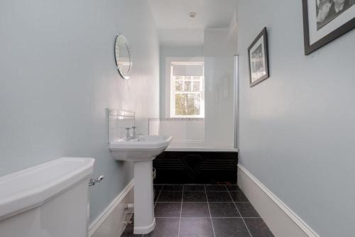 a white bathroom with a sink and a window at Balcraig House in Maybole