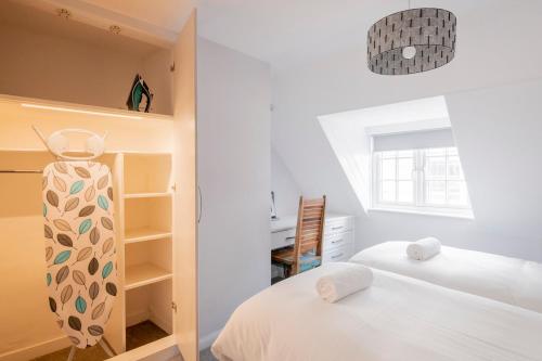 a white bedroom with two beds and a window at 3-bedroom apartment in the heart of Brighton's Lanes in Brighton & Hove