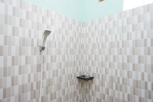 La salle de bains est pourvue d'une douche carrelée de blanc et d'un sèche-cheveux. dans l'établissement RedDoorz near Yogyakarta International Airport, à Glagah
