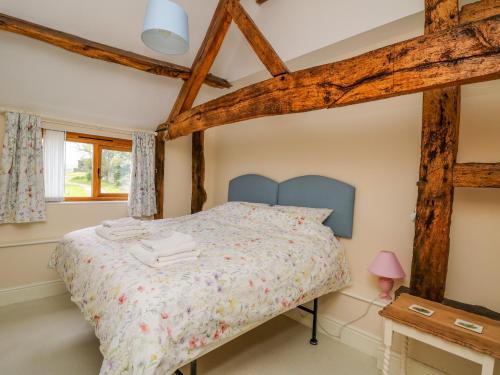una camera con letto in una stanza con travi in legno di Goblaen Barn a Builth Wells