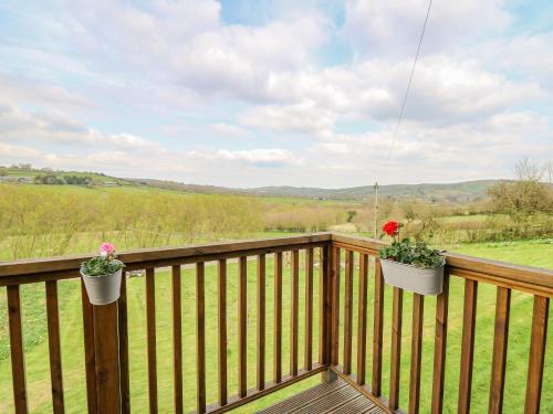 a balcony with two flower pots on a wooden fence at Goblaen Barn in Builth Wells