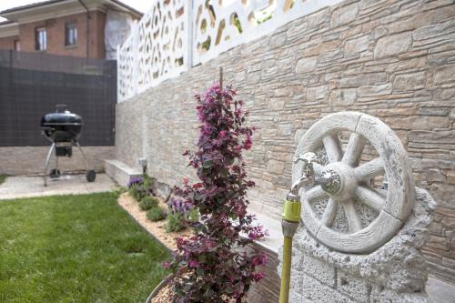 a stone wall with a wheel and purple flowers at WiBnB Holiday rentals- appartamenti in Turin