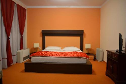 a bedroom with a bed with an orange wall at Hotel Lukavac in Lukavac