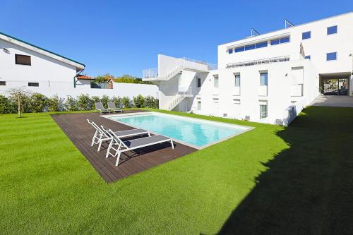 a swimming pool with chairs and a building at Uporto House Residence in Porto