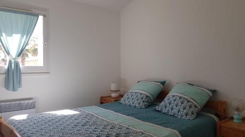 een slaapkamer met een bed met kussens en een raam bij Les 5 palmiers in Valras-Plage