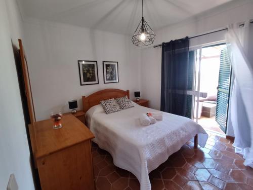 a bedroom with a bed and a table and a window at 51 VilaMar - Casas & Papeis in Porches