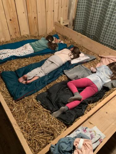 three girls laying on mats on hay in a pen at Le grenier à paille in Rhodes