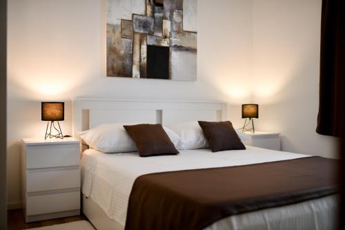 a bedroom with a white bed with two lamps at White Hill Apartment in Zadar