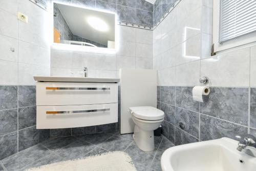 a bathroom with a toilet and a sink and a mirror at White Hill Apartment in Zadar