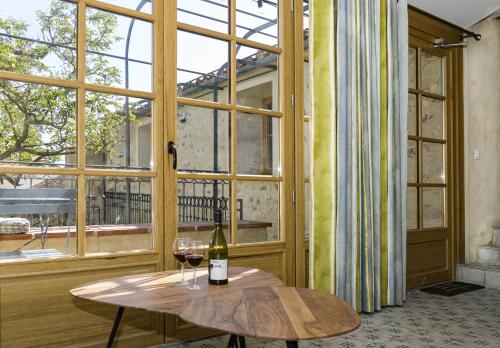 - une table avec une bouteille de vin et deux verres dans l'établissement Cottage - La Maison du Château - By DOMAINE RIBERACH, à Bélesta