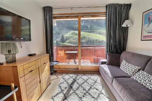 un salon avec un canapé et une grande fenêtre dans l'établissement Residence Olympie I, à Méribel