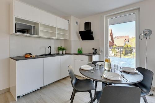 a kitchen and dining room with a table and chairs at BURSZTYNOVA Apartamenty Piamola in Kąty Rybackie