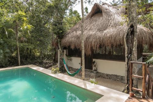 a resort with a swimming pool and a thatched hut at Blue Monkey Chemuyil in Chemuyil