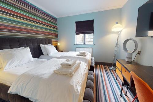 a hotel room with two beds and a mirror at Village Hotel Maidstone in Maidstone