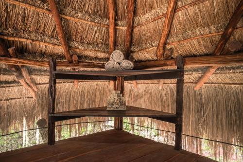 a room in a thatched hut with a shelf at Blue Monkey Chemuyil in Chemuyil