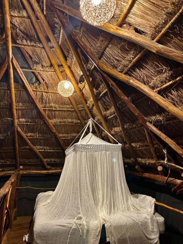 a bed in a straw roofed room with a chandelier at Blue Monkey Chemuyil in Chemuyil