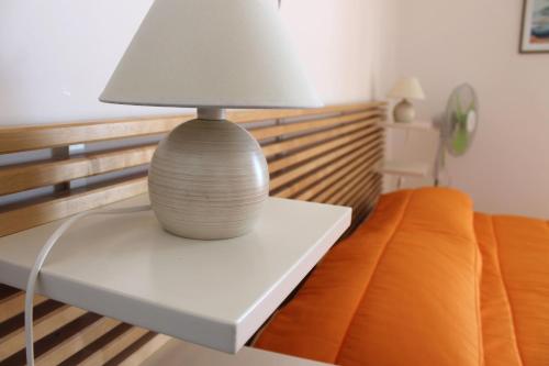 a lamp sitting on a white table next to a bed at Vent In Costa Ospitalità Diffusa in Furore